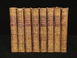 five old books are lined up on a black surface