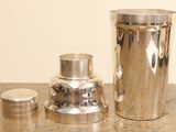 a silver vase and a silver shaker sitting on a table