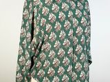 a woman ' s green shirt with white and pink flowers on it