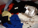 a pile of clothes that is sitting on a bed