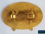 a close up of a gold plate with a pin on it