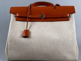 a white and brown bag with a brown handle on a gray background