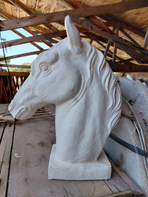 une statue représentant une tête de cheval posée sur une table en bois