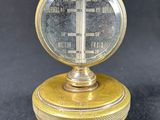 antique brass plated thermometer on a black background