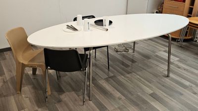 une table blanche avec quatre chaises et un ordinateur portable posé dessus