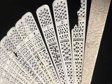 plusieurs éventails en papier blanc portant des inscriptions, posés sur une surface noire