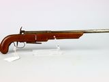 un vieux pistolet au canon en bois posé sur une surface blanche