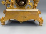 a gold clock with angels and cherensils on it