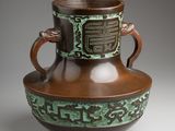a brown and green vase sitting on a table
