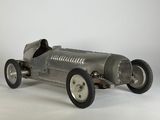 une maquette en métal d'une voiture de course posée sur une surface blanche