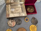 une table sur laquelle se trouvent une boîte en argent et un tas de pièces d'or