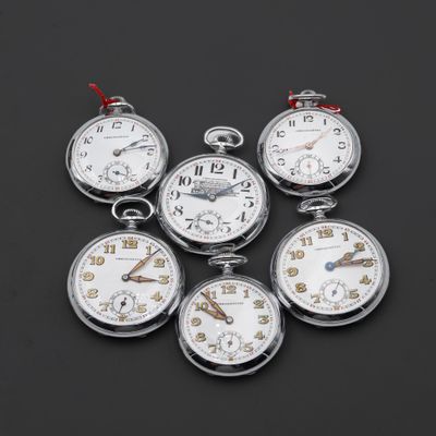 cinq montres de poche en argent avec des cadrans blancs sur un fond noir