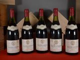 six bottles of wine are lined up on a red table