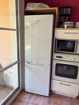 un réfrigérateur et un four dans une cuisine située à côté d'une porte-fenêtre coulissante