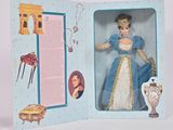une photo d'une poupée dans une boîte sur laquelle figure la photo d'une femme