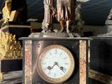 une statue représentant une femme en train de lire un livre à côté d'une horloge