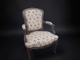 une vieille chaise avec un dossier et des accoudoirs tapissés de fleurs