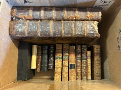 de nombreux vieux livres dans une boîte en carton posée par terre
