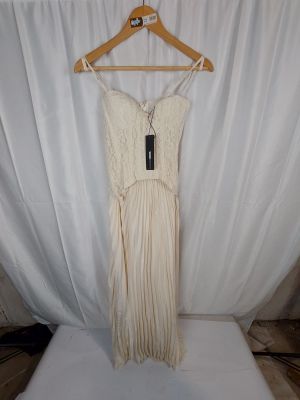 La robe est suspendue à un cintre devant un rideau blanc.