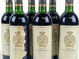 six bottles of wine are lined up in a row on a white surface