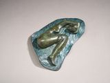 sculpture of a woman laying on a rock in the water
