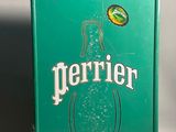 une boîte verte sur laquelle figure une bouteille de Perrier