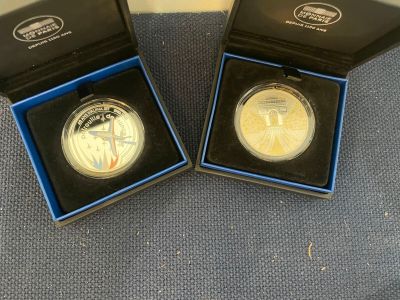 two silver and gold coins in a black box on a blue surface