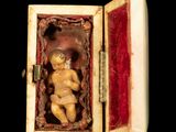 a small box with a small doll inside of it