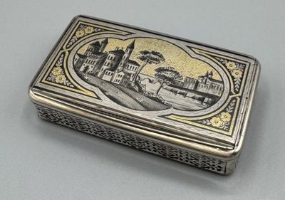 une vieille boîte en argent sur laquelle est représentée une ville