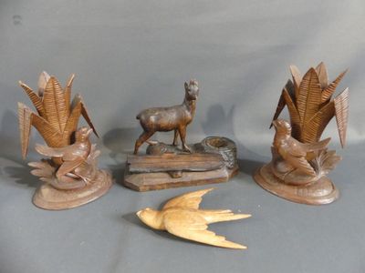 three wooden sculptures of birds, a deer, and a bird on a table