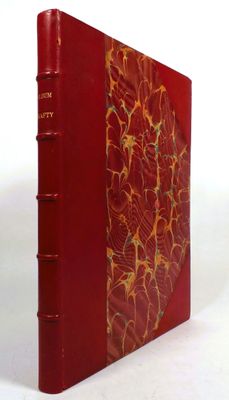an old red book sitting on top of a table next to a white wall