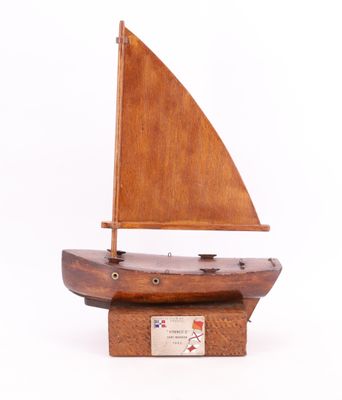 maquette en bois d'un petit voilier posée sur un socle en bois