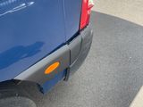 the rear end of a blue van parked in a parking lot