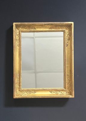 une image représentant un miroir à cadre doré accroché à un mur noir