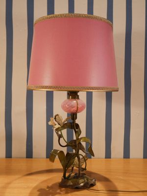 une lampe rose posée sur une table en bois, avec un mur rayé en arrière-plan