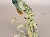 a figurine of a peacock sitting on a tree branch