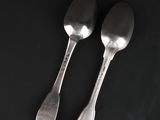 two silver spoons on a black surface with a black background