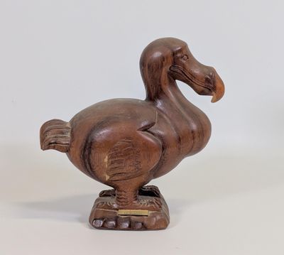 une image représentant une statue de canard en bois posée sur une surface blanche