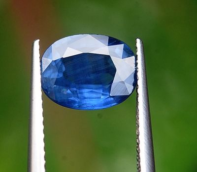 un gros plan sur une pierre bleue tenue par une pince