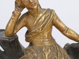 a gold clock with a statue of a woman sitting on top of it