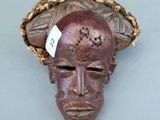 une image représentant un masque en bois coiffé d'un chapeau