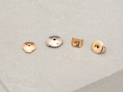 three pairs of gold and silver stud earrings sitting on top of a white surface
