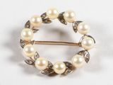 une image représentant une broche ornée de perles et de feuilles sur fond blanc
