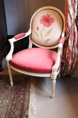 a chair with a pink cushion in front of a fireplace