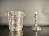 a silver bucket and a silver candle holder on a table