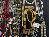 many different necklaces and bracelets laid out on a table