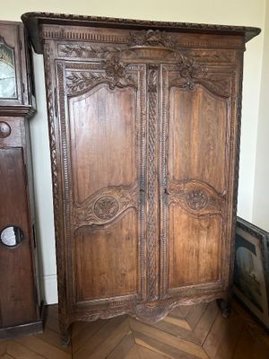 a large wooden armoire with a clock on top of it