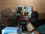 a room with a refrigerator, a chair, a table, and other items in it