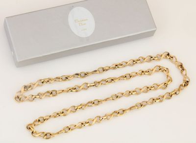 a close up of a gold chain with a box on a white surface