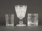 trois verres et un gobelet en verre posés sur une table